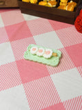 Minty Blossom Cake Roll Mini Taba Squishy from Mini Street Bites Series on a cute mini food display